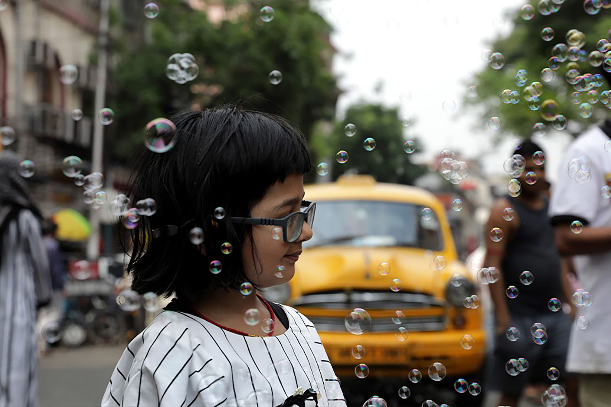 Image of a girl walking down the street surrounded by bubbles.