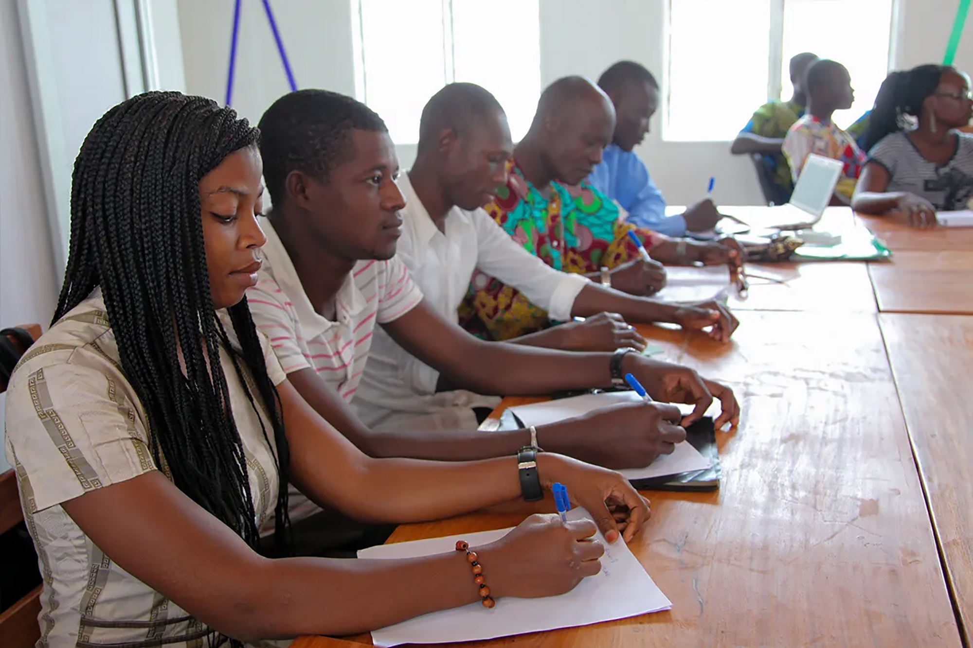 A group of people taking notes and paying attention during a meeting.   