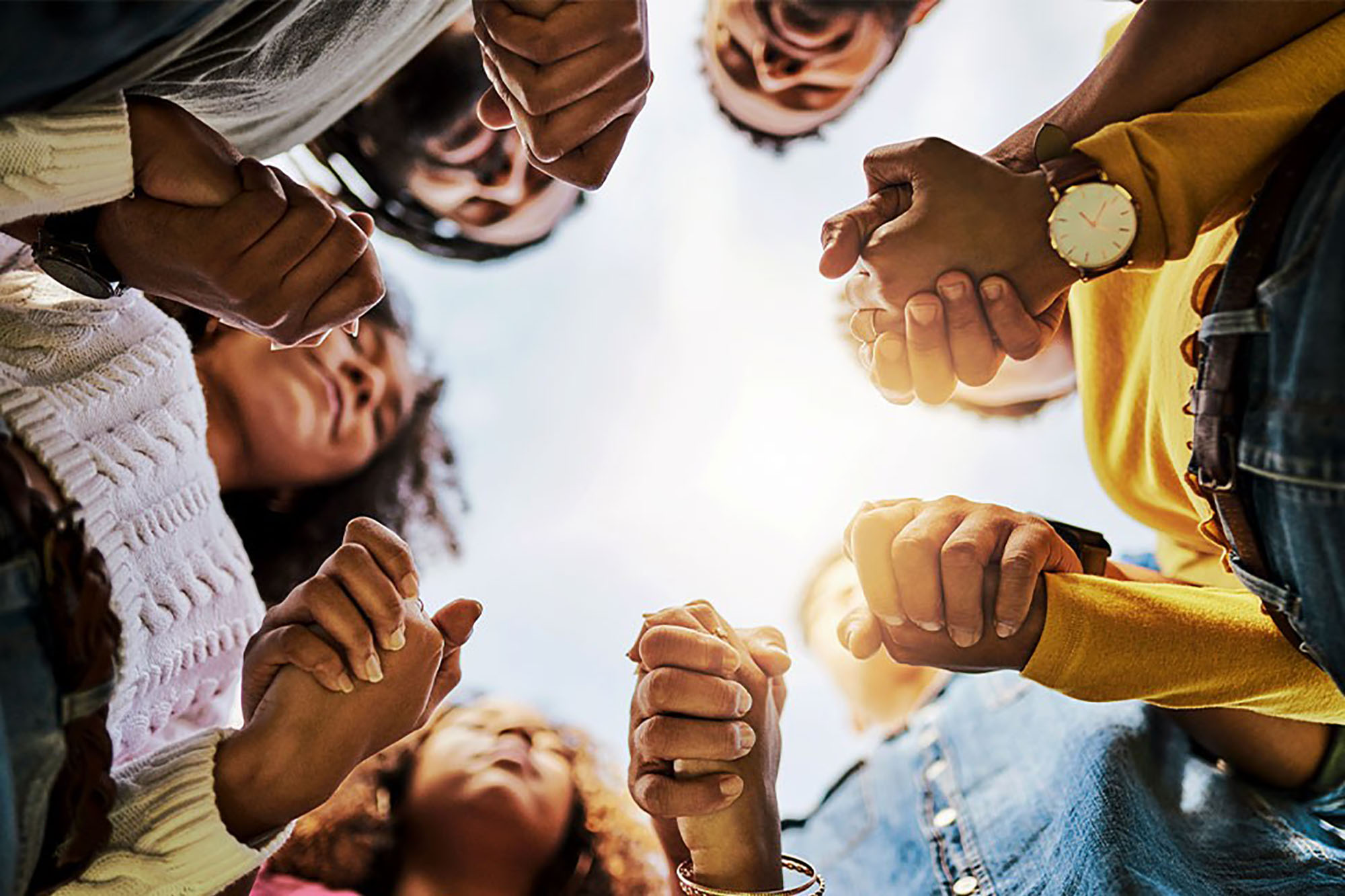 A group of youngsters holding hands and closing their eyes.