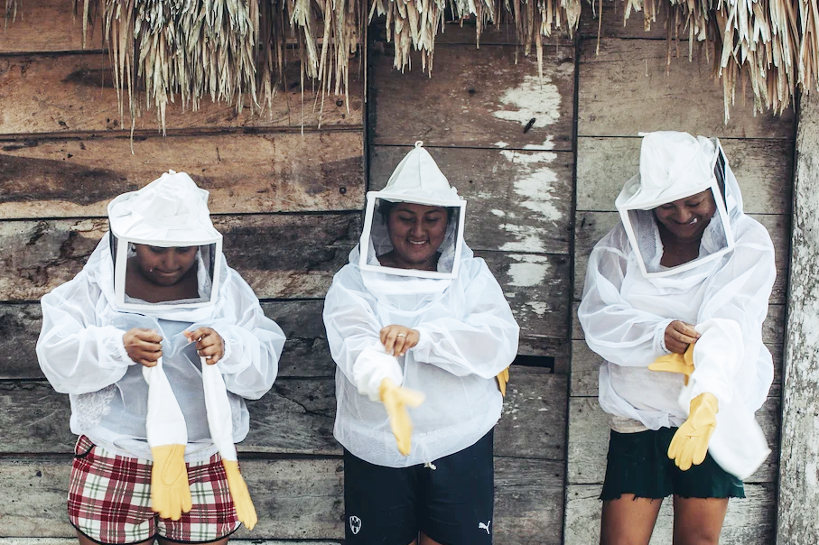 A group of three women dressing in their honey collection gear.