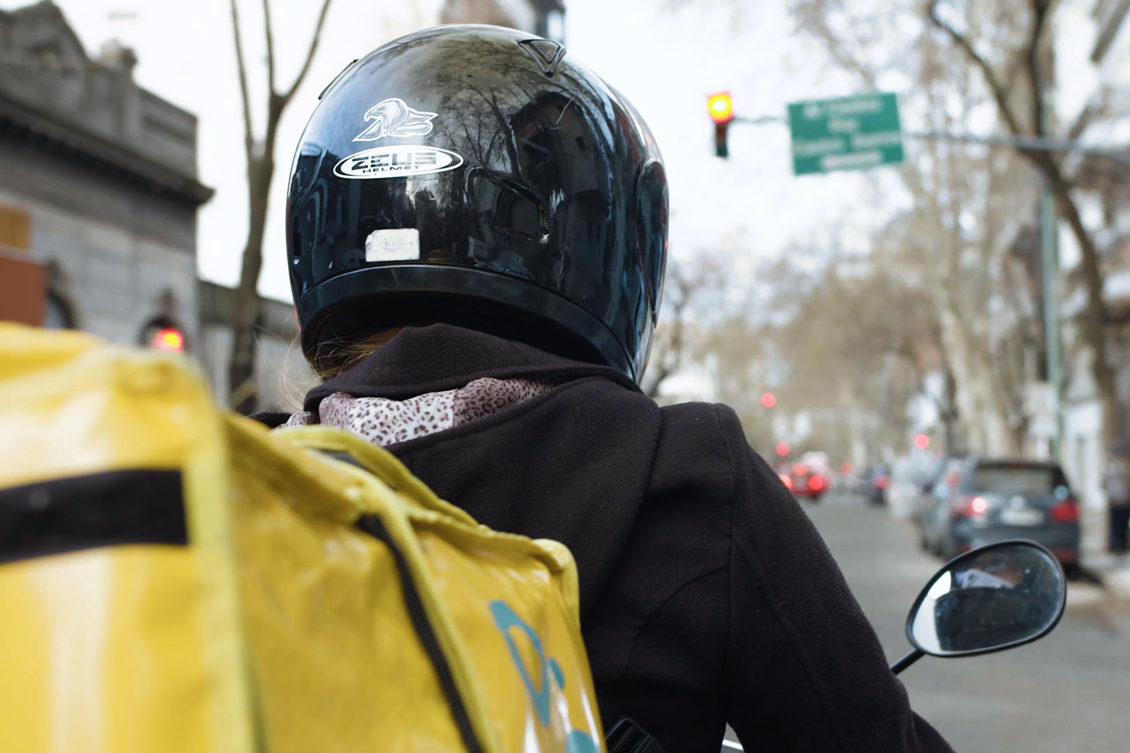 A delivery person on a motorbike on the streets.
