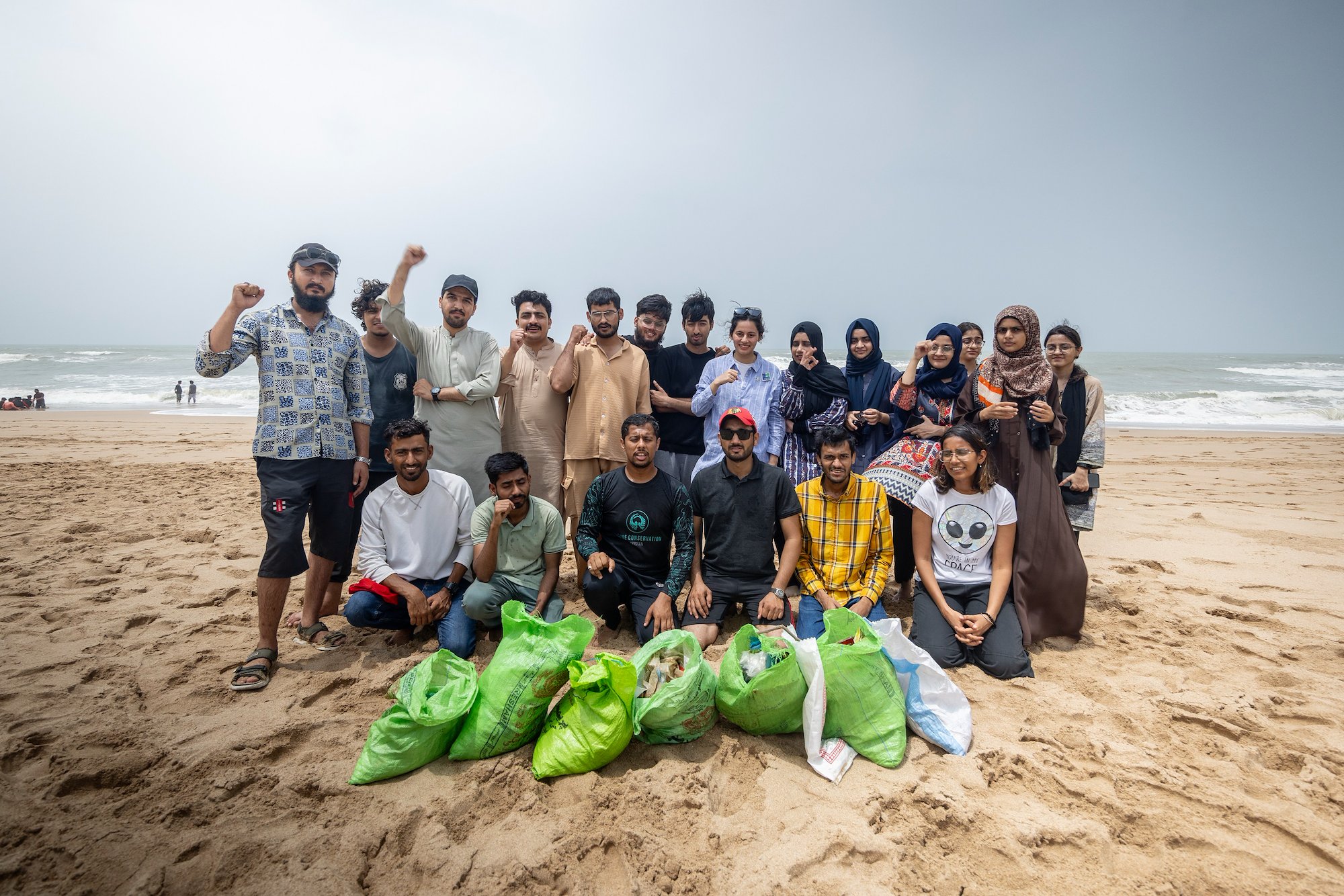 group of youths posing on beach with bags