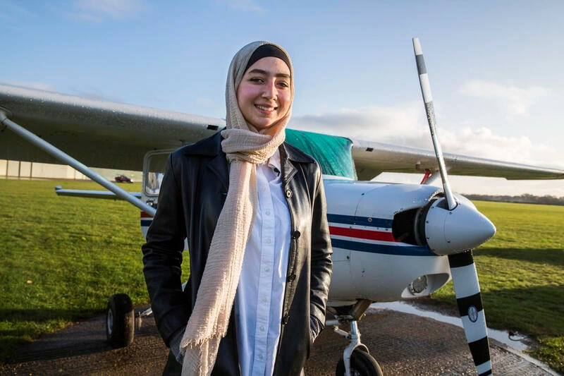 Una chica de 20 años posa junto a un avión.