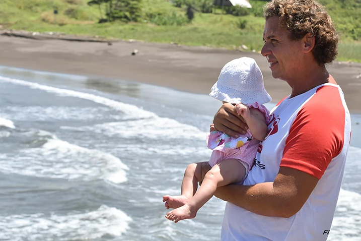 man on a beach holding a baby