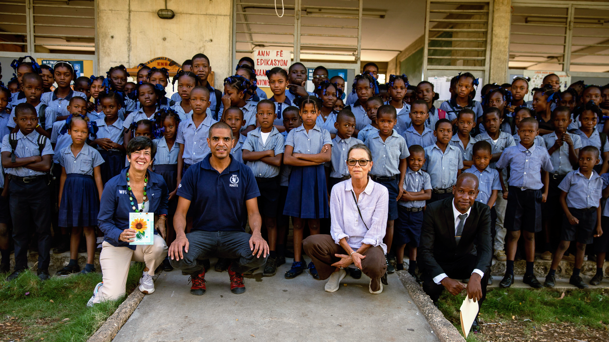 Ulrika Richardson, Lola Castro, and WFP staff take a group photo with school children