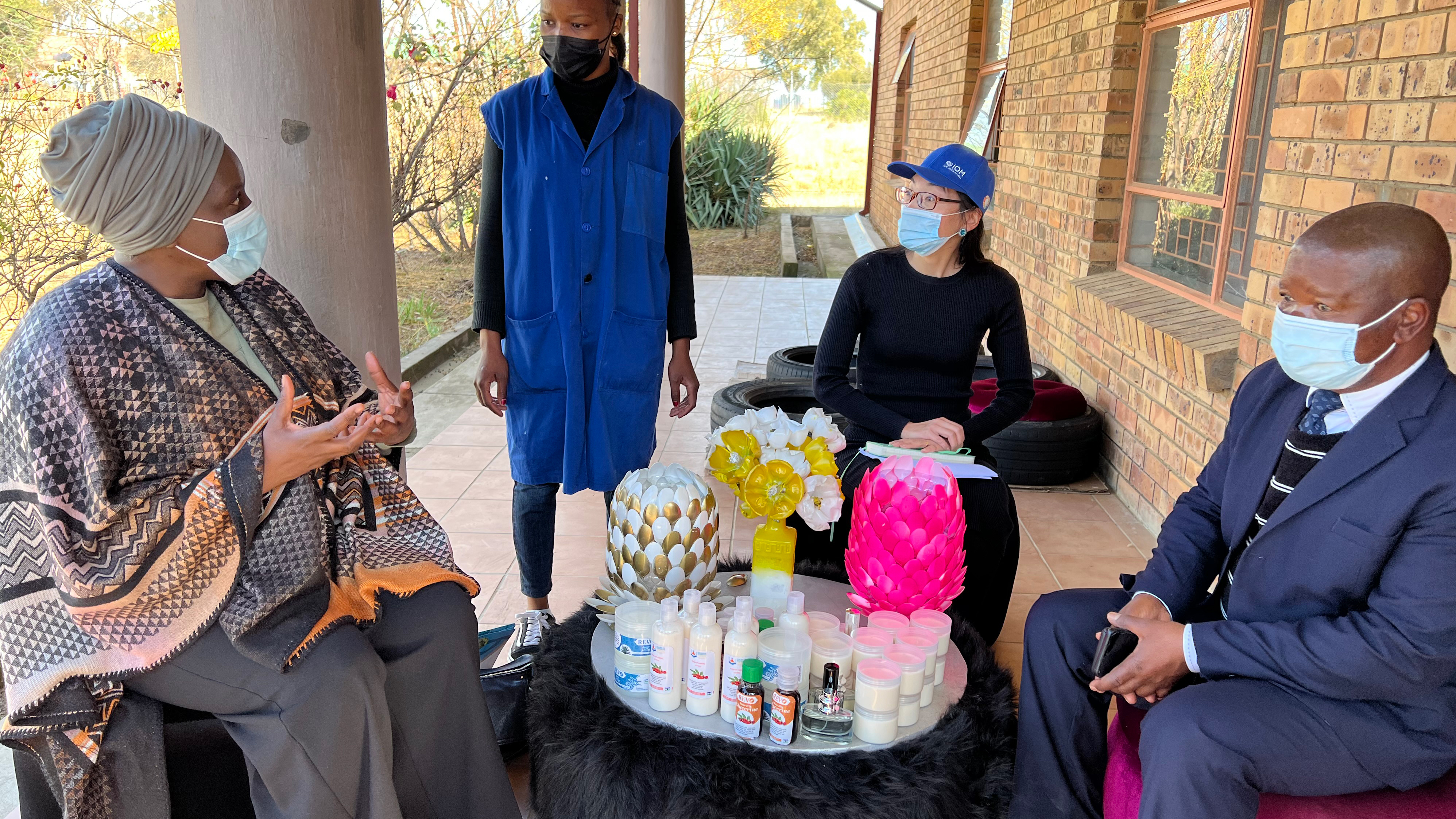 Mukwashi seated in an outdoor patio and engaged in conversation with others