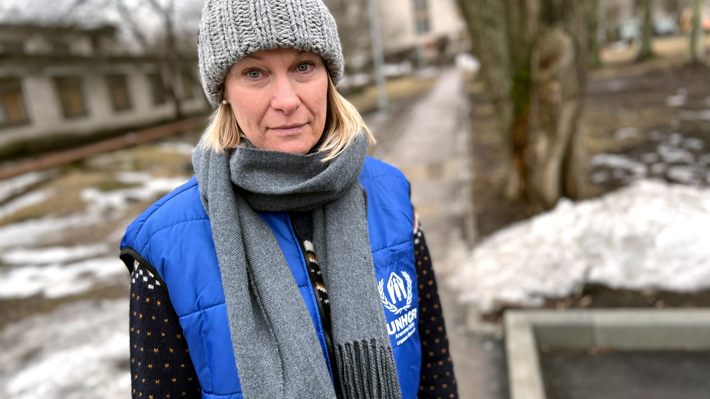 Karolina is pictured in the snowy outdoors wearing a knitted grey hat and UNHCR vest