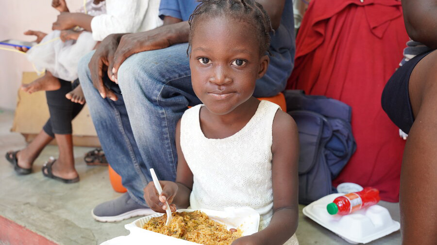 Girl eats amongst a group of seated people