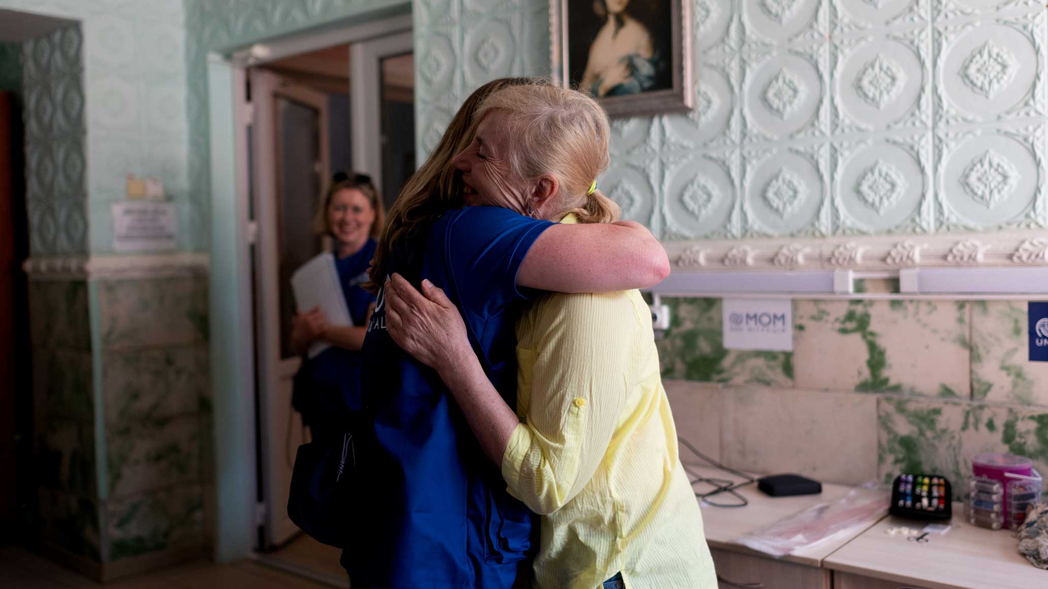 Amy hugs a woman while another looks on from the background