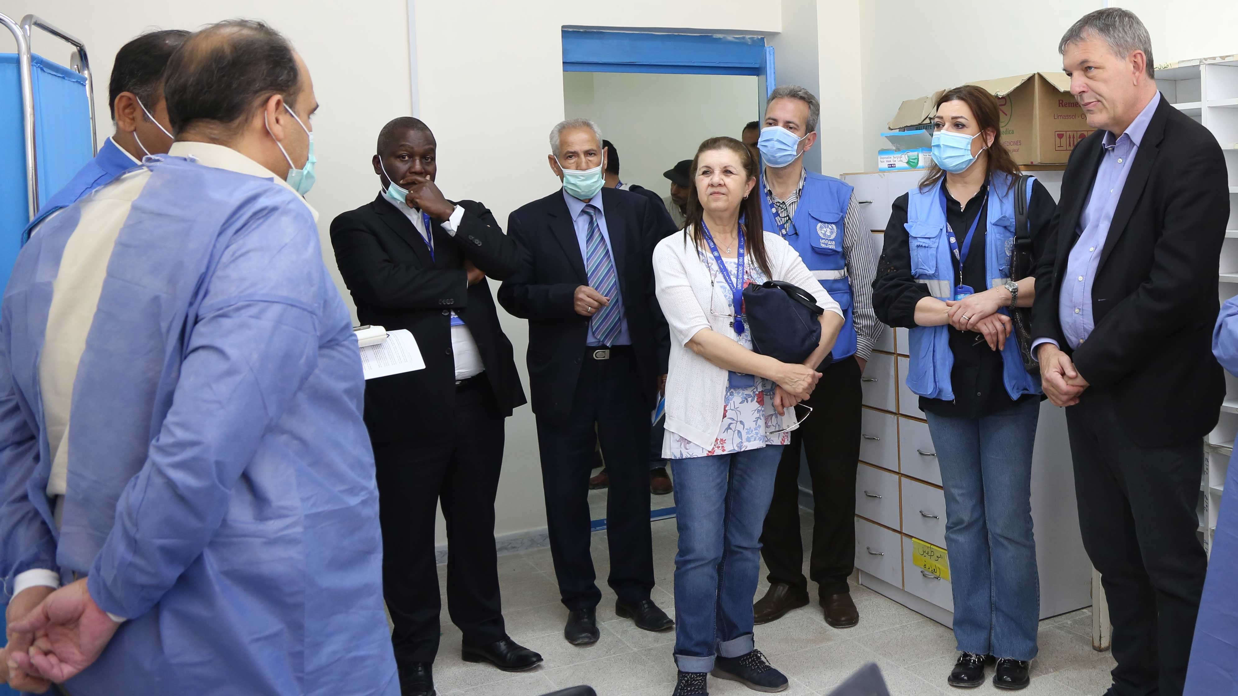 Lazzarini stands inside a hospital room is in discussion with medical service professionals and staff