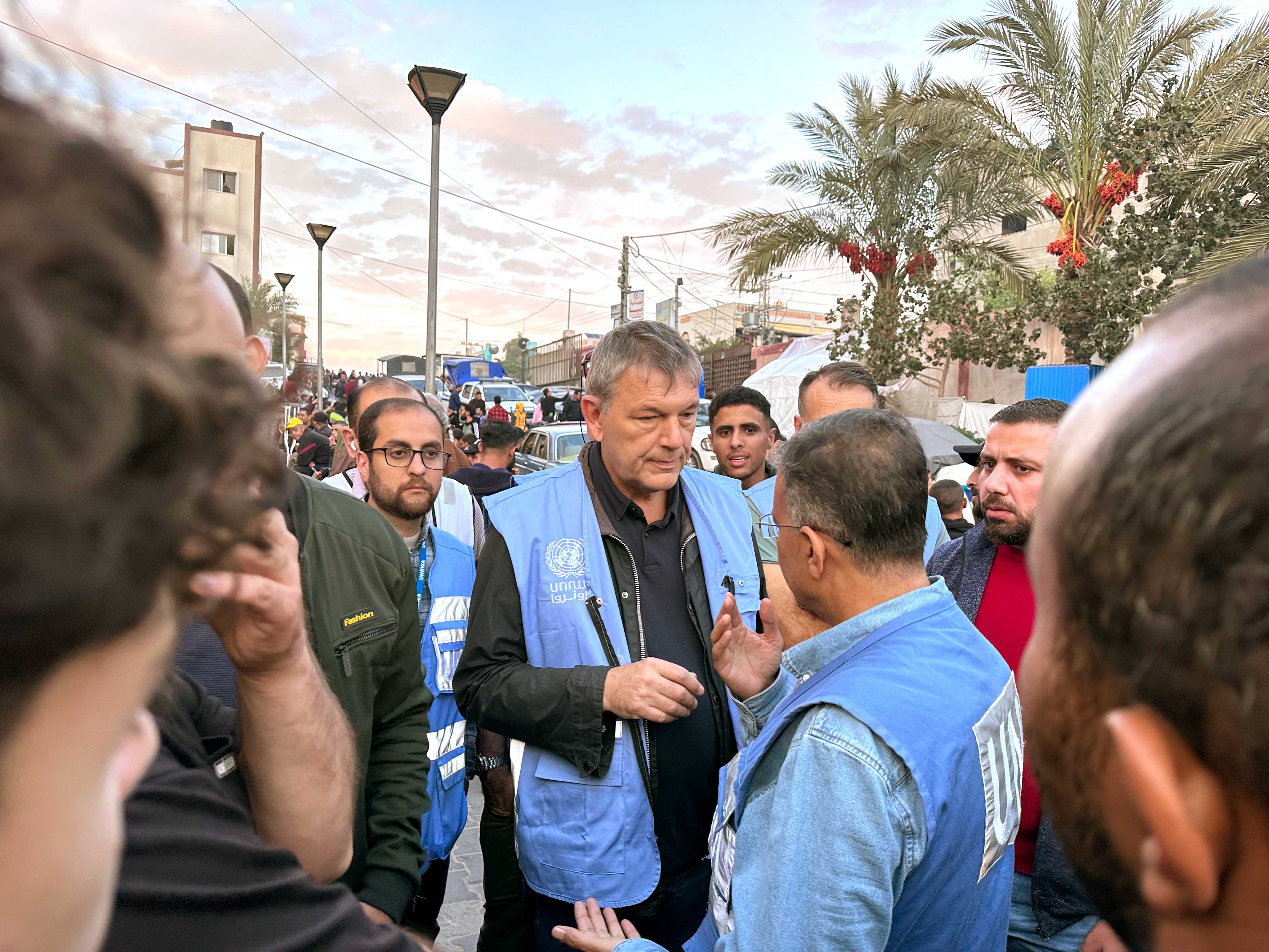 Lazzarini is seen outdoors within a crowd as he speaks with UNRWA colleagues all wearing the blue UNRWA vest