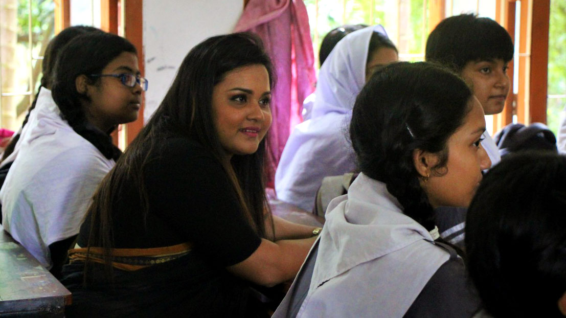 Jayathma sits in a room with many young children in school uniforms