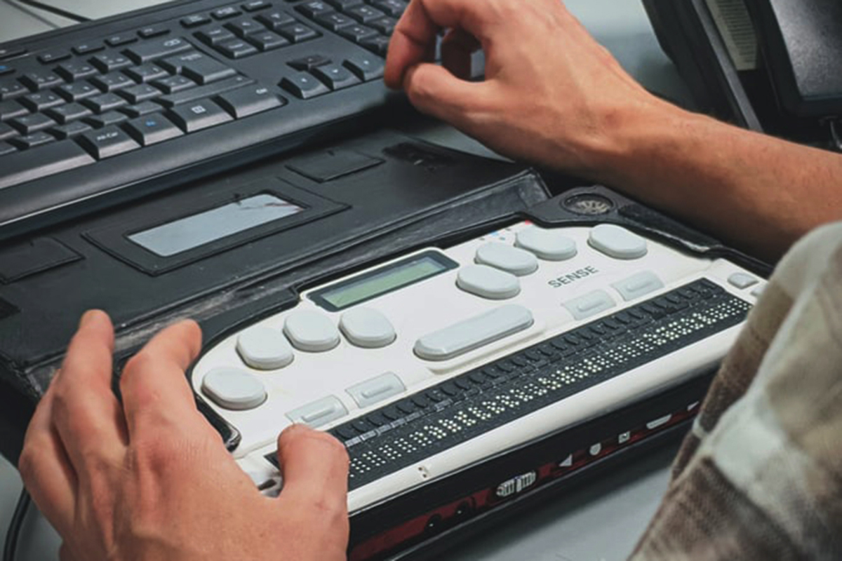 Hands over a braille screen reader in front of a keyboard