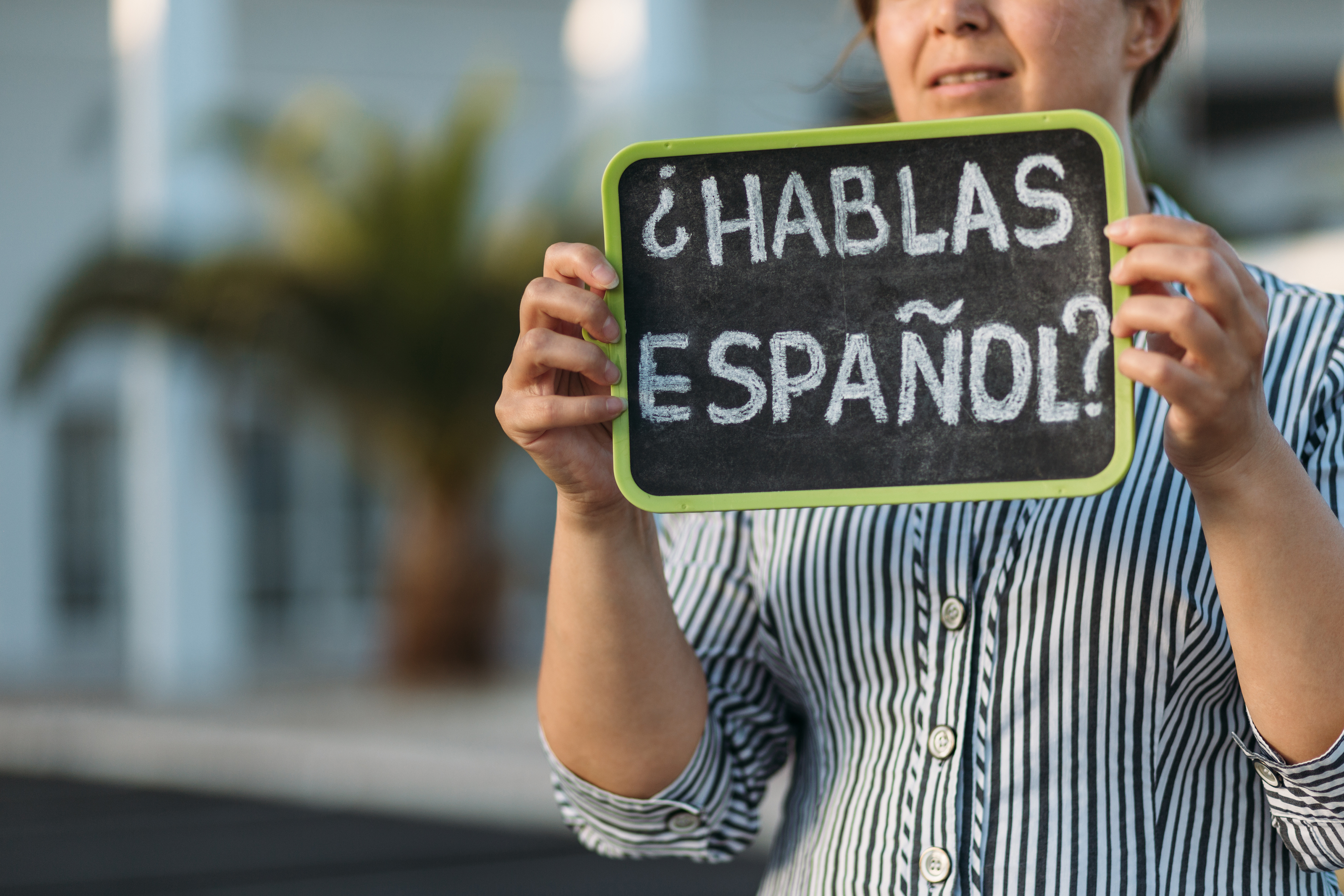 Mujer con una pizarra donde se lee: ¿Hablas español?