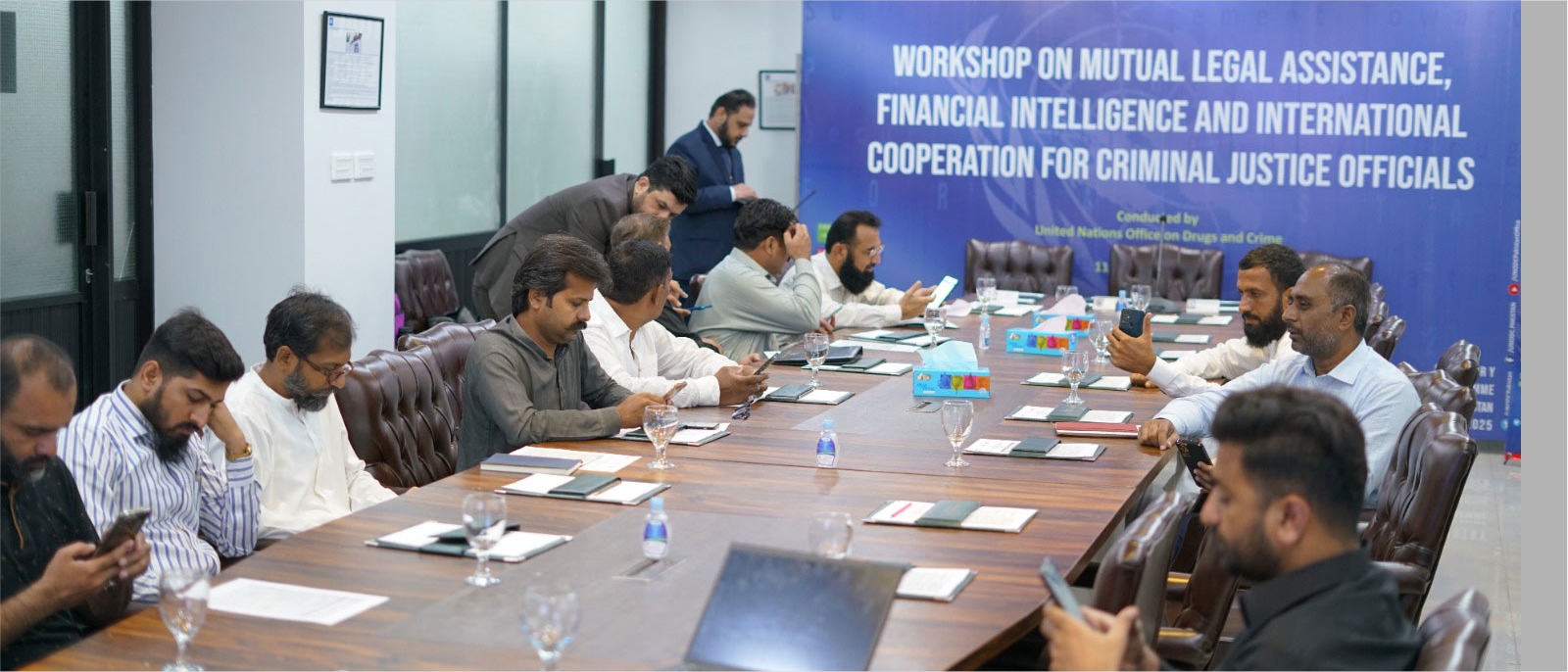 men seated on a long table with a banner announcing the workshop at the top of the table