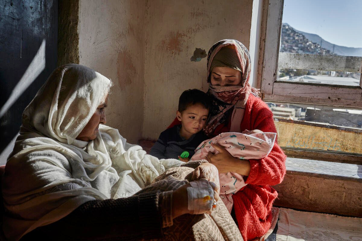 elderly woman and mother with baby and young child in a bare room