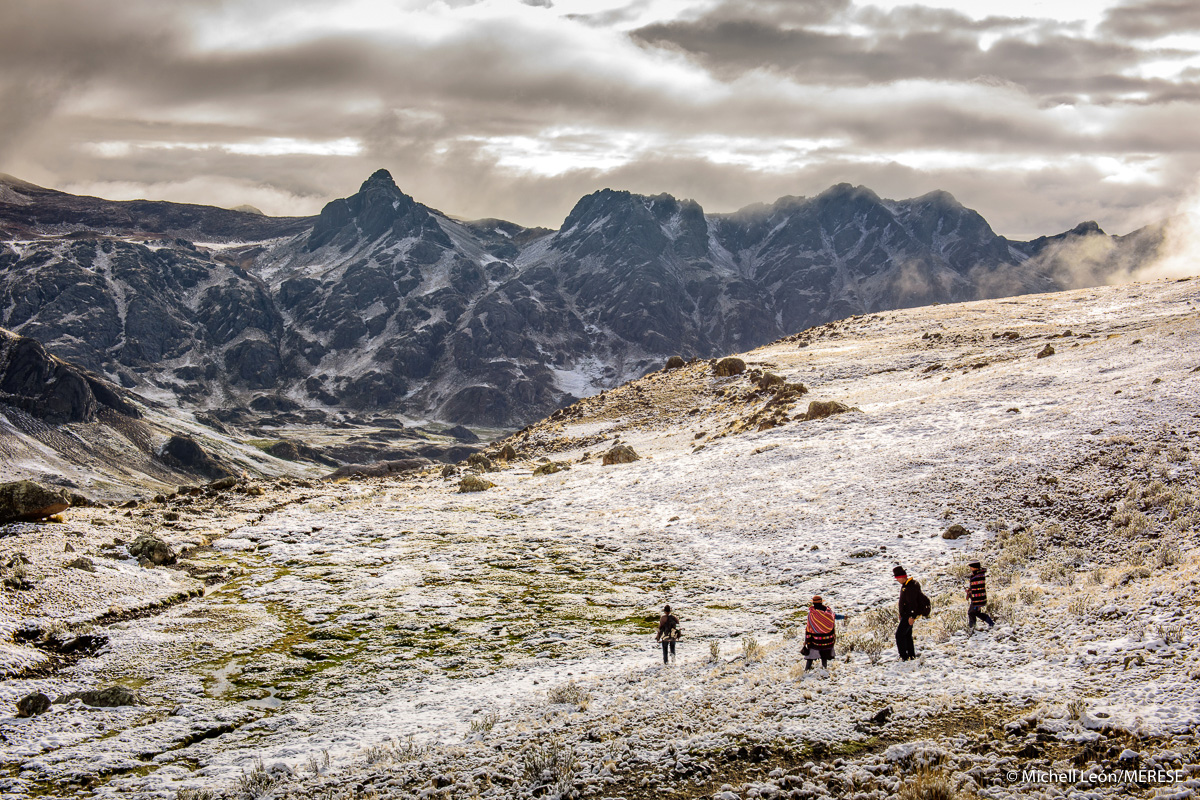 A group of people walk through a frosty mountain landscape.
