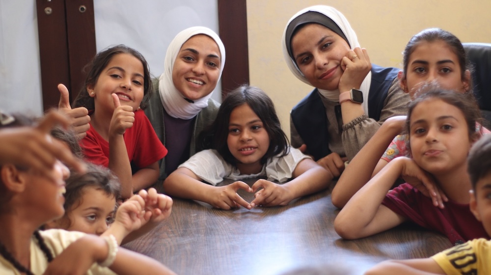 A photograph showing a group of people sitting at a table looking at the camera and smiling