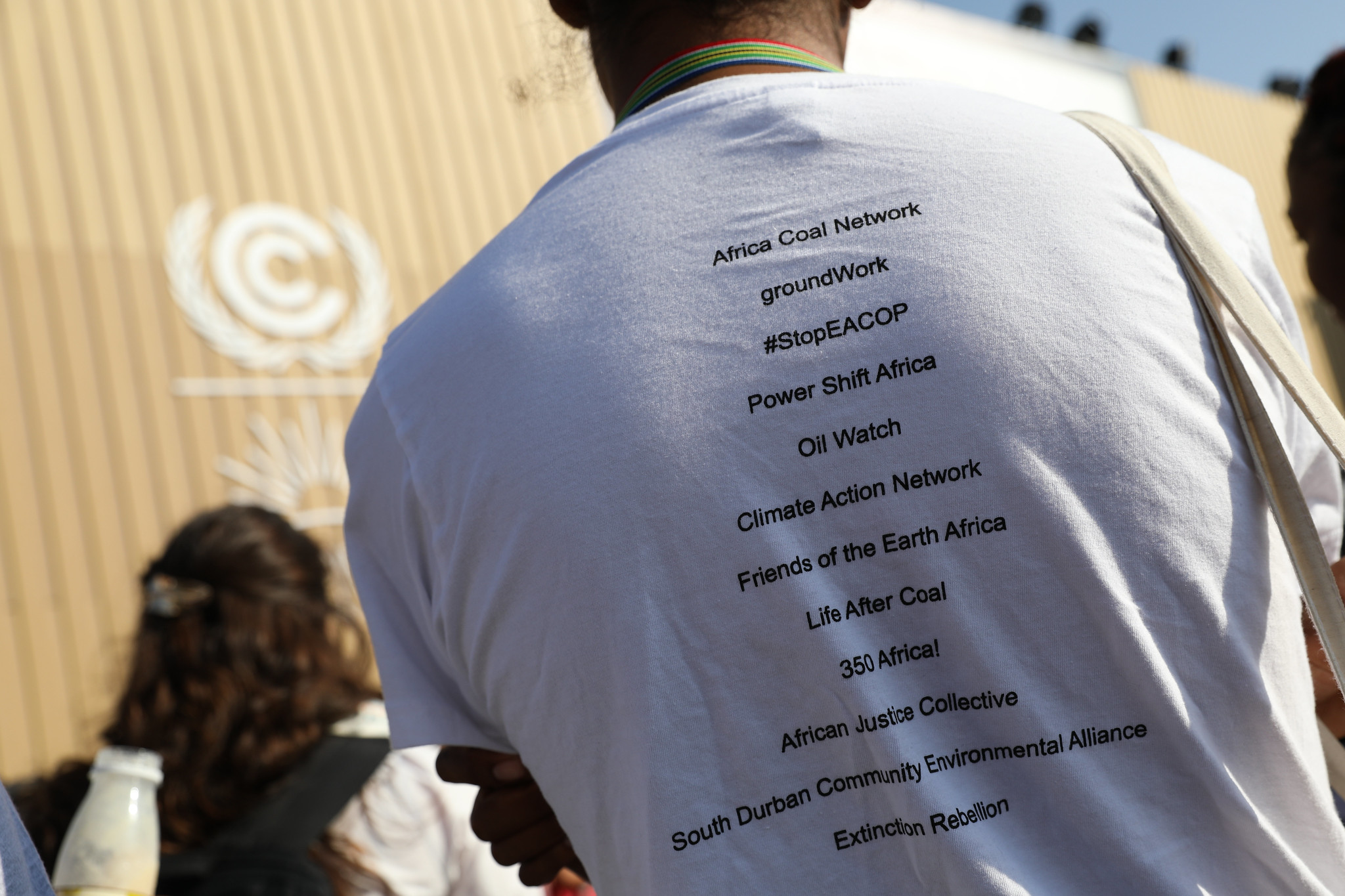 A photo of the back of a white t-shirt with the name of iniciatives and alternatives to oil and gas exploration