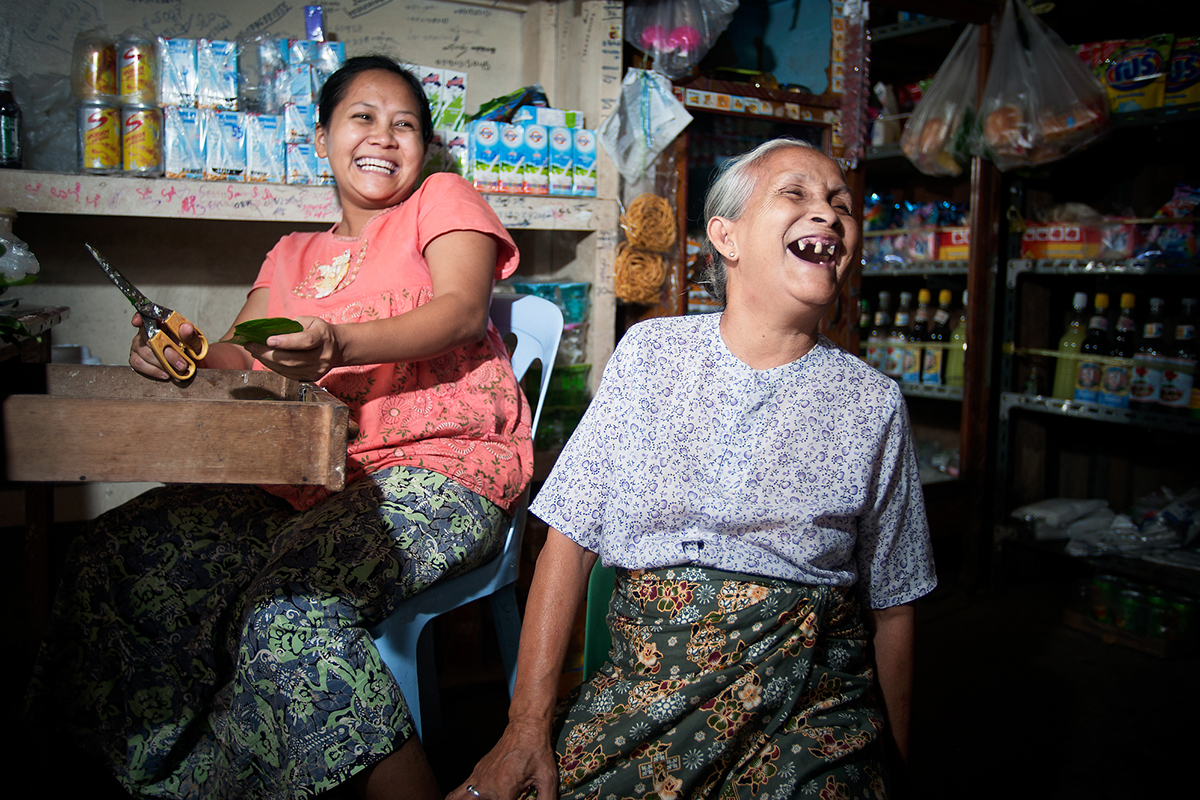 An older woman inside a grocery store laughs next to another woman.