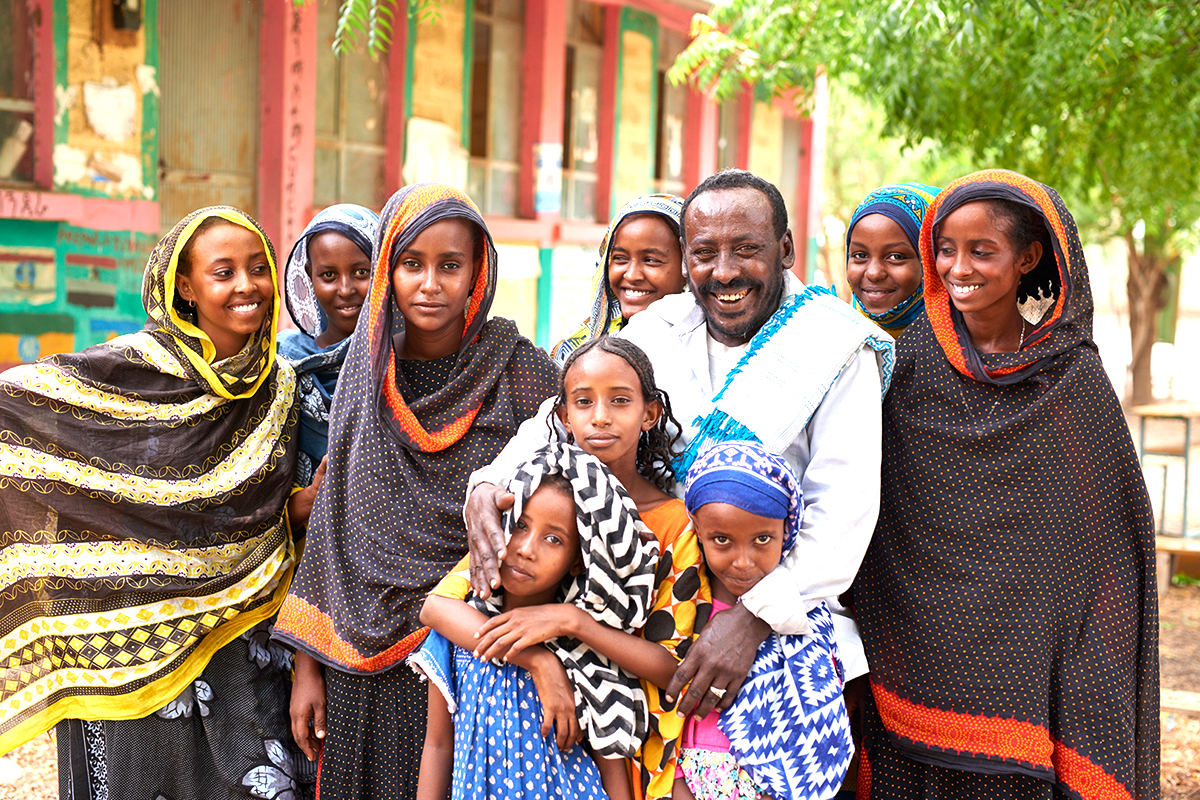 A father surrounded by his nine daughters. 