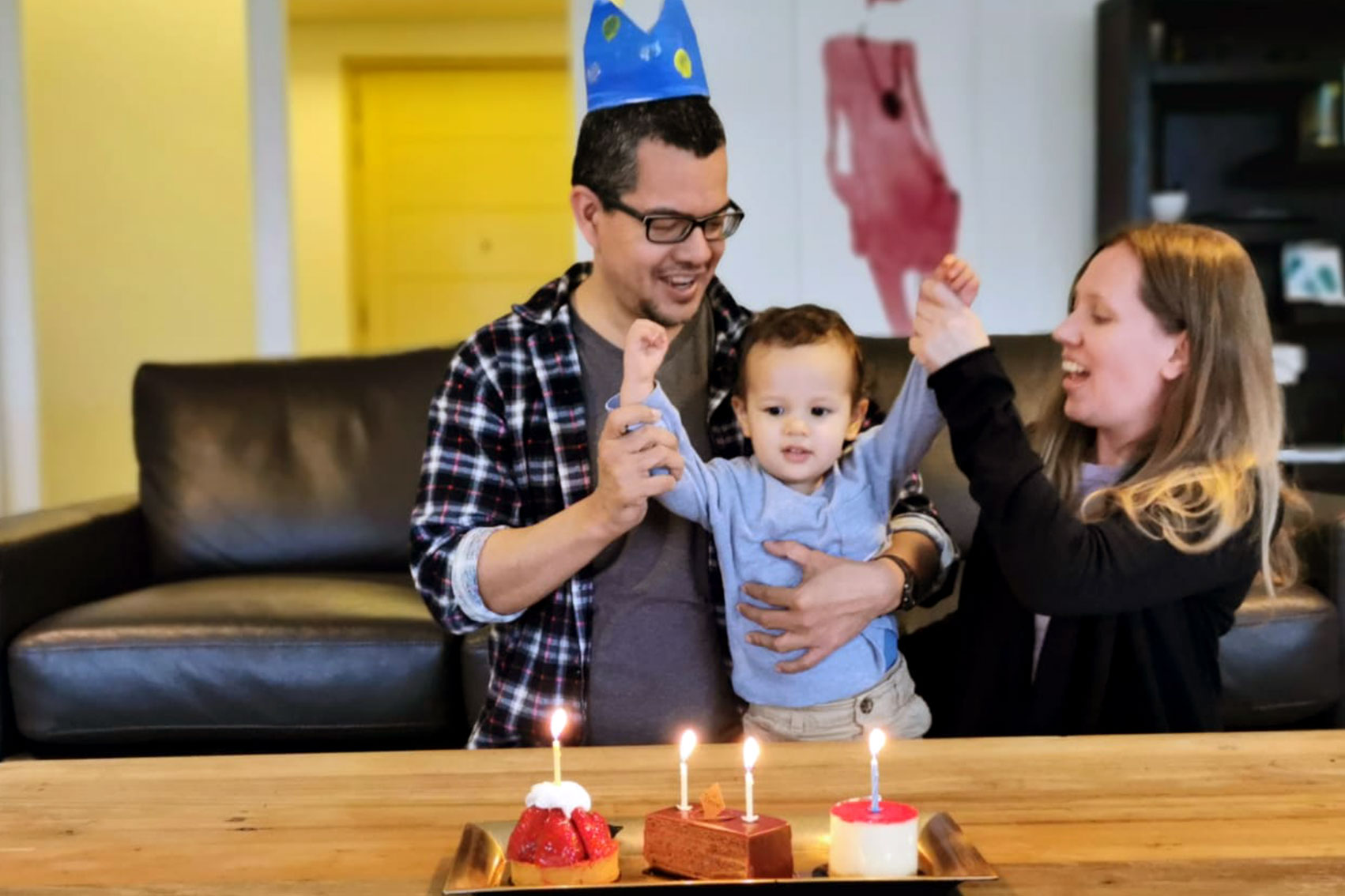 Sarah with husband and Issac celebrating the child's birthday with a cake and candles.