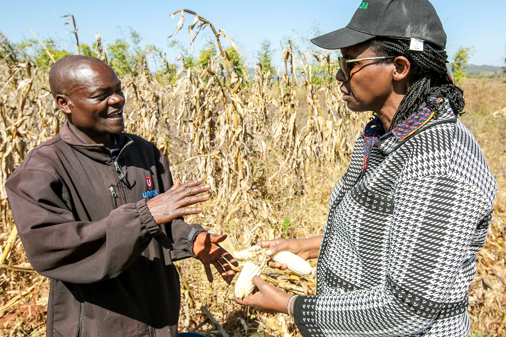 Dr. Kalibata speaking with a farmer in an open field of corn.