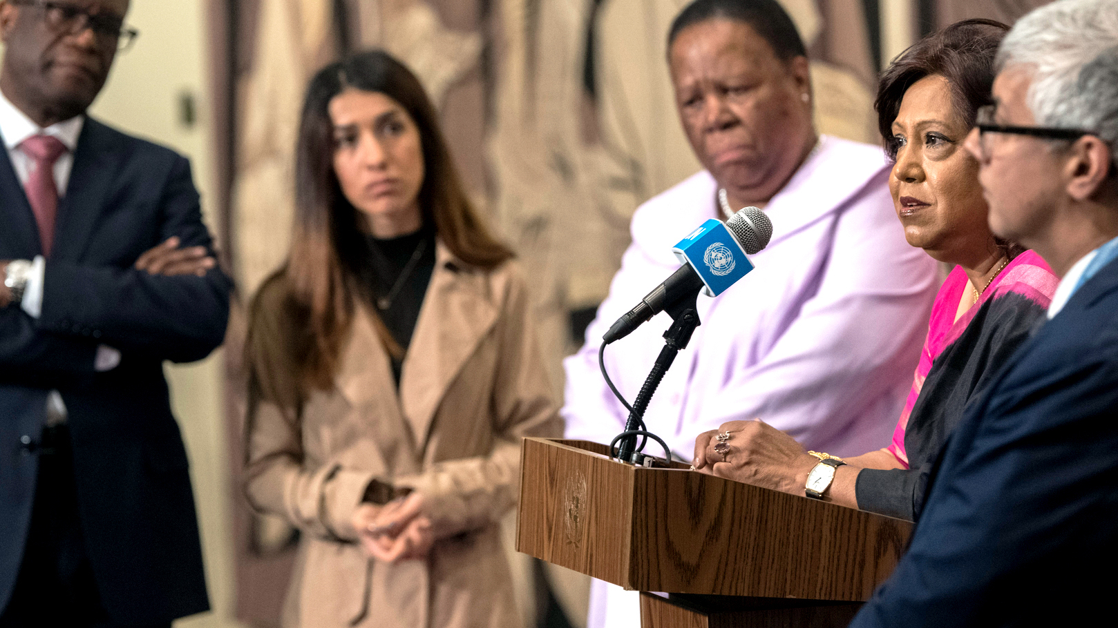 Pramila Patten speaks at the podium surrounded by advocates.