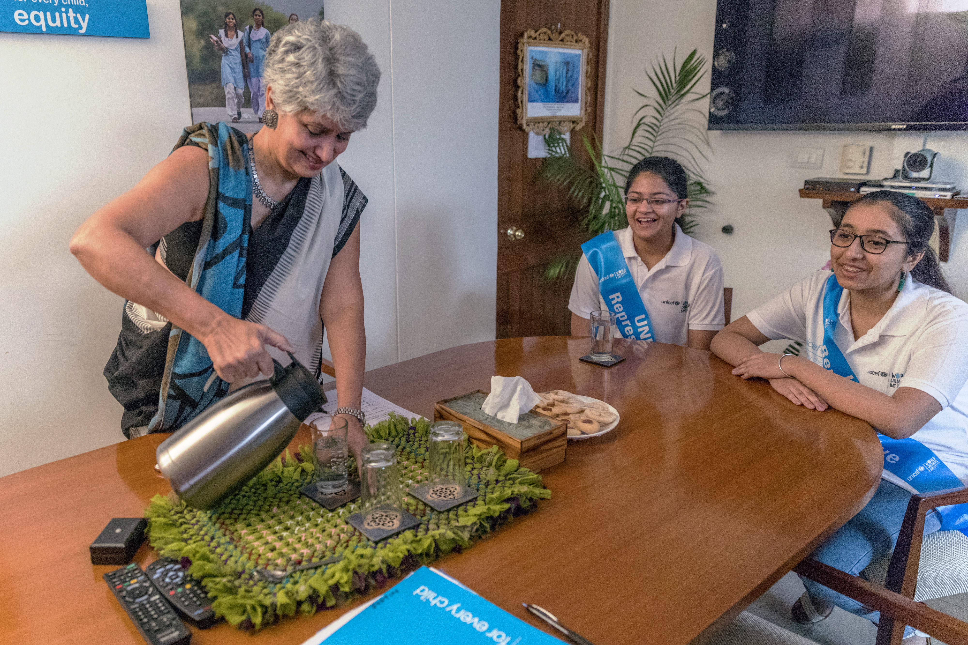 Yasmin welcomes 2 young adolescent girls with tea.