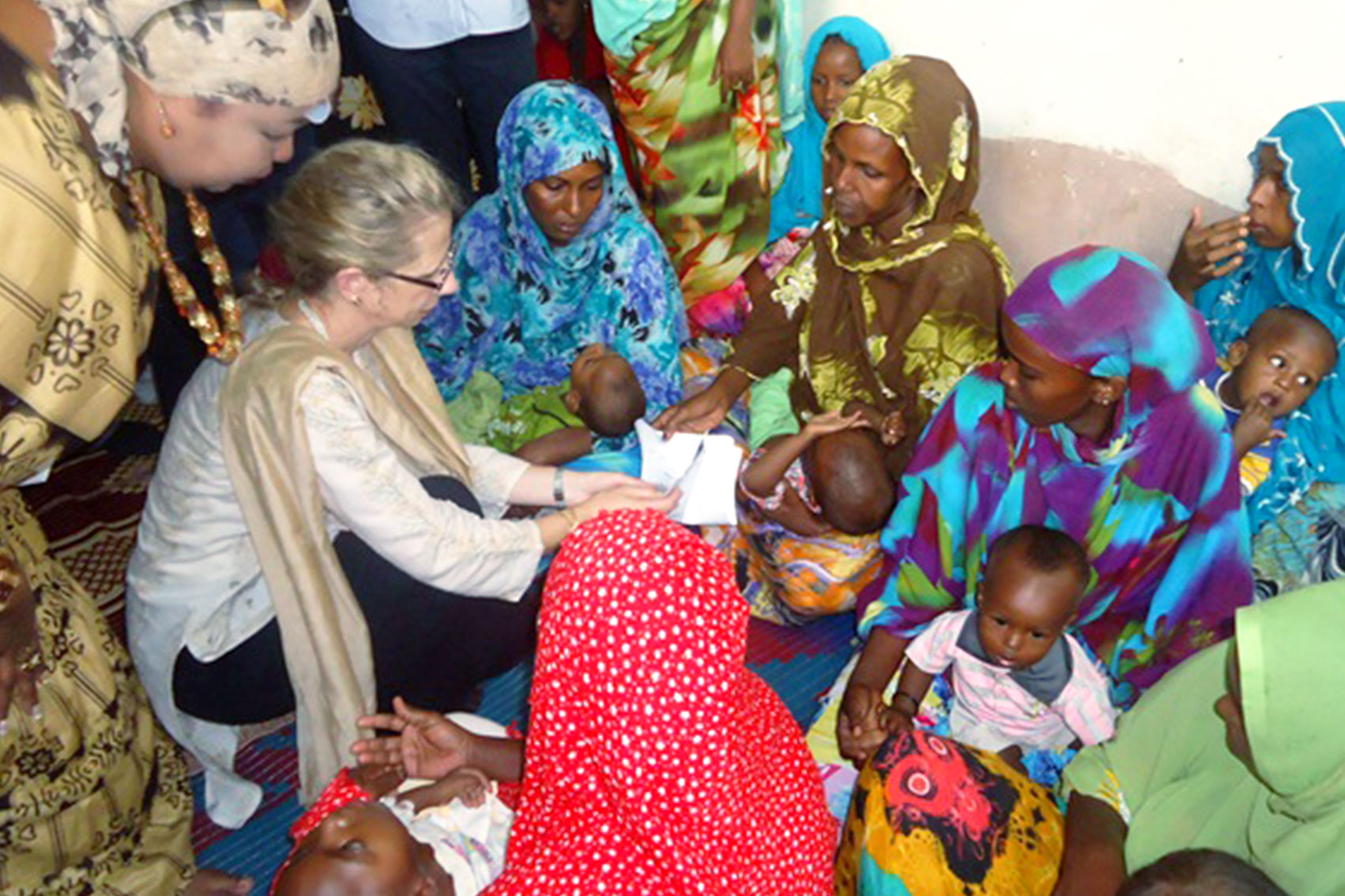 Inger Andersen is surrounded by women and children in a maternal health facility.