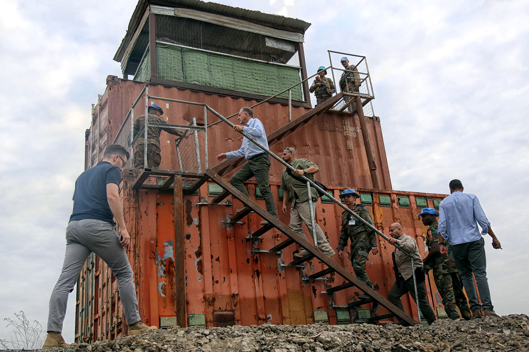 David Shearer walks with a group of people up an exposed staircase attached to a small tall structure.