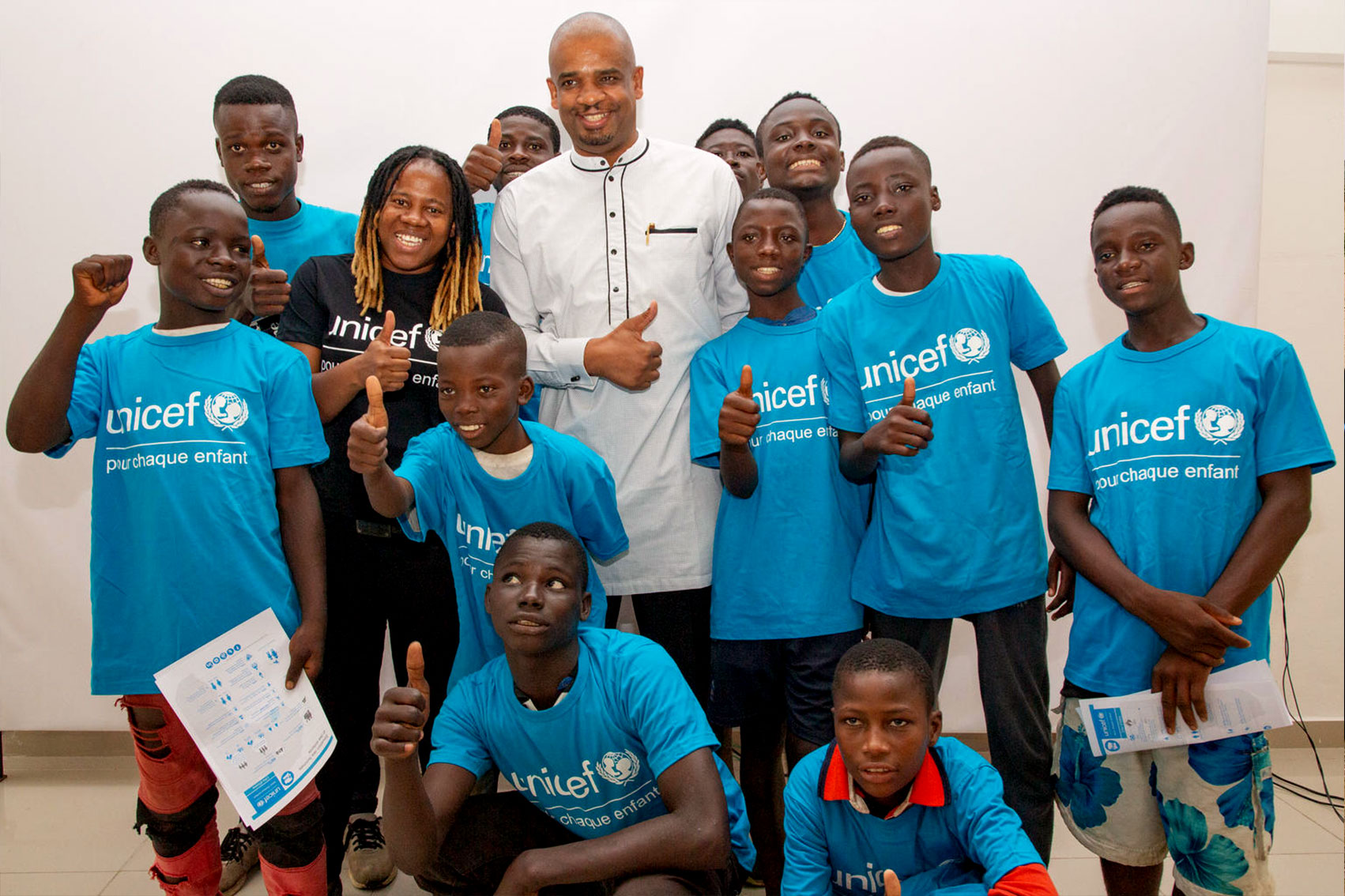 Rapper NASH poses for a photo with children and Aboubacar.