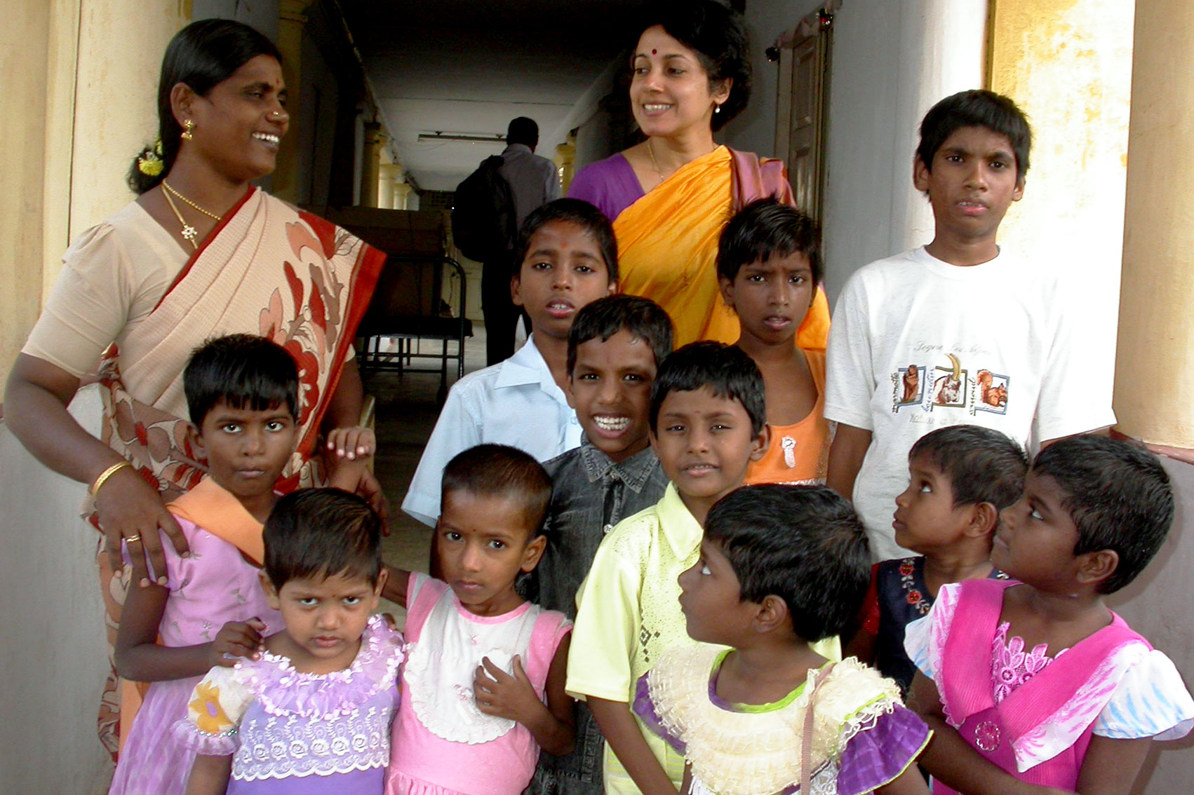 Dr. Soumya Swaminathan and a woman stand for a photo op surrounded by children.