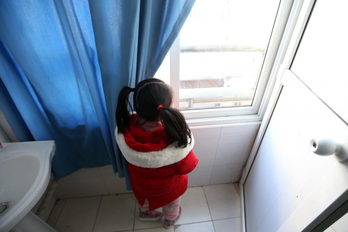 young girl stands by window in bathroom