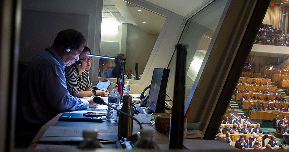 Intérpretes trabajando en una cabina en el salón de la Asamblea General.