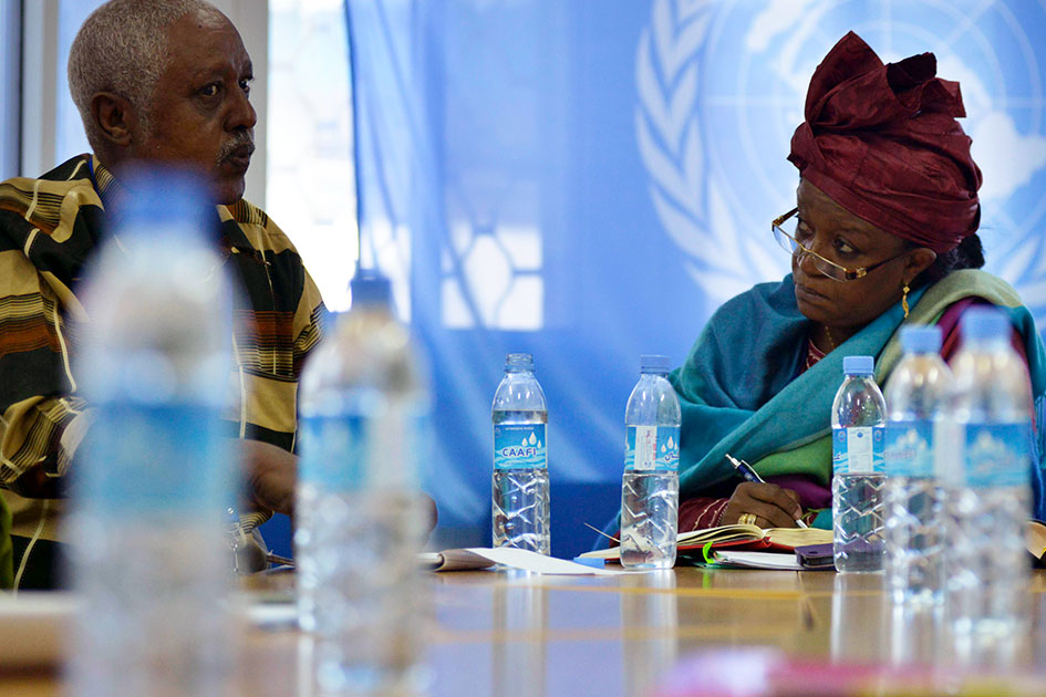 Bangura, seated at a table, is in deep discussion with a member of the Police Advisory Committe.