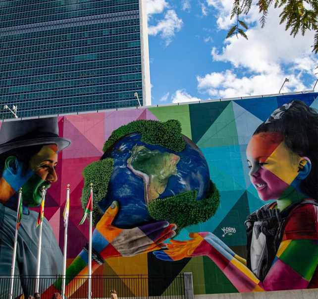 Vista del mural de Eduardo Kobra en la sede de la ONU donde se ve a un hombre entregando un globo terráqueo a una niña.