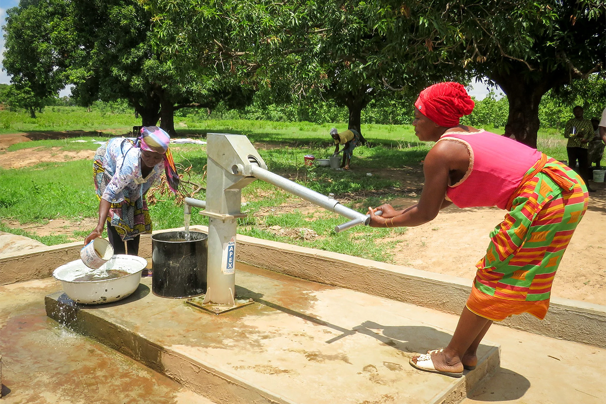 two women using a manual water pump