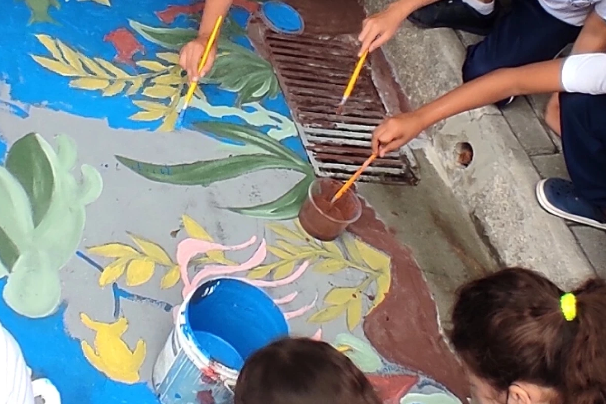 Grupo de niños pintando dibujos en el suelo.