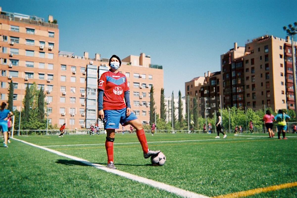 A woman in football uniform poses with a football. 