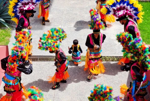 Grupo de personas vestidos con coloridos trajes regionales durante un espectáculo.