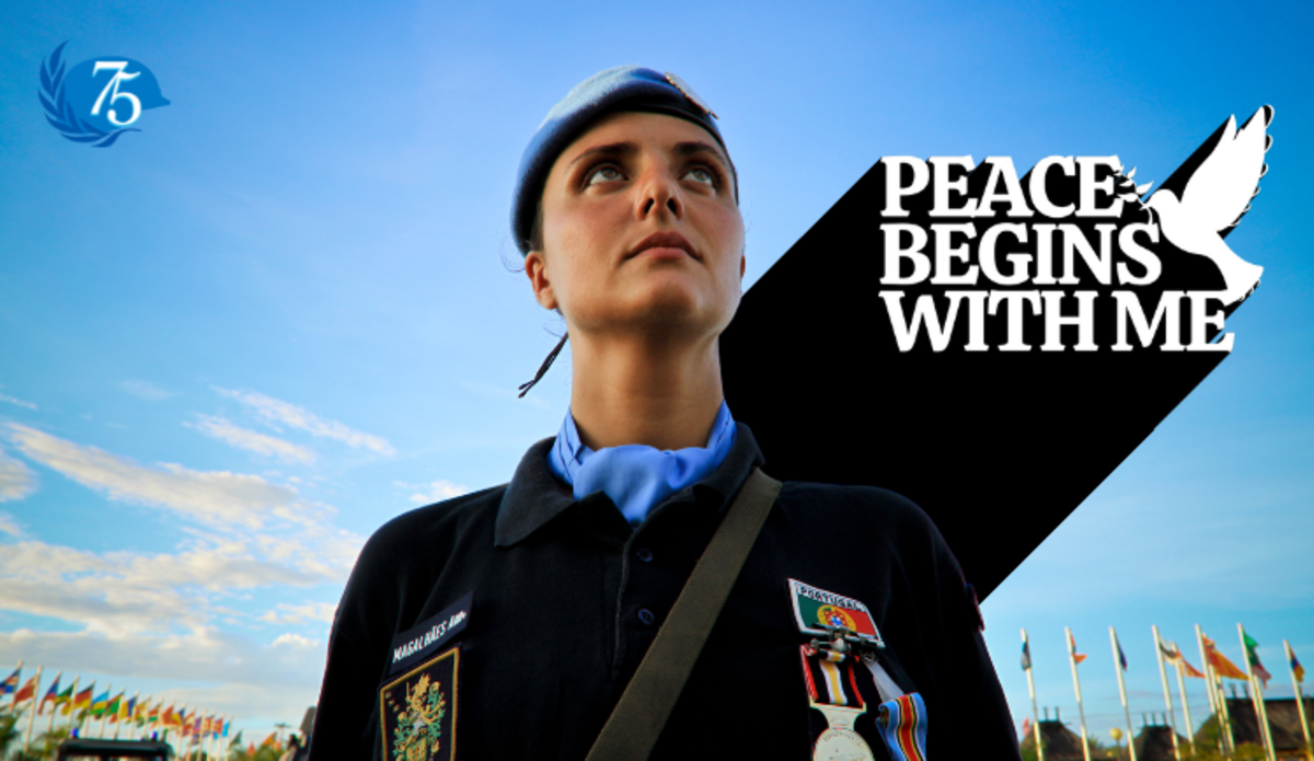 A female UN peacekeeper in uniform gazes solemnly at the sky.