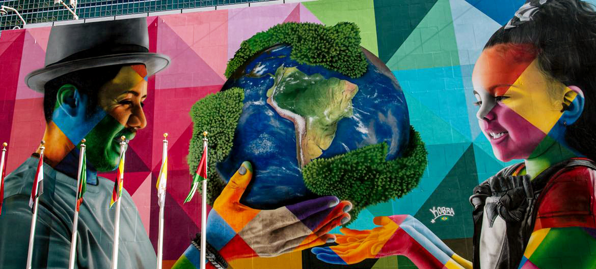 Mural outside UN Headquarters on New York’s First Avenue by Artist Eduardo Kobra and his team, depicting an older person handing over the globe to a young child