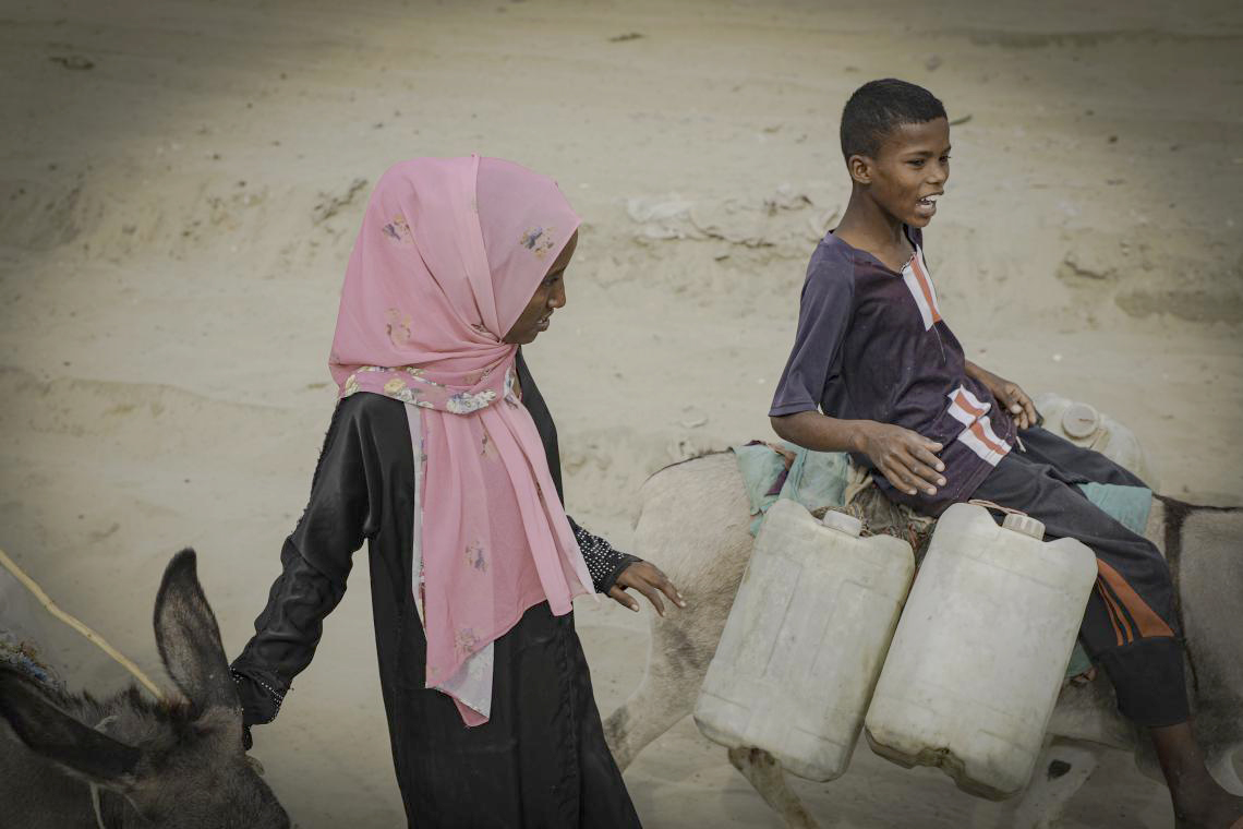 Nagat fetches water with two donkeys and a young man