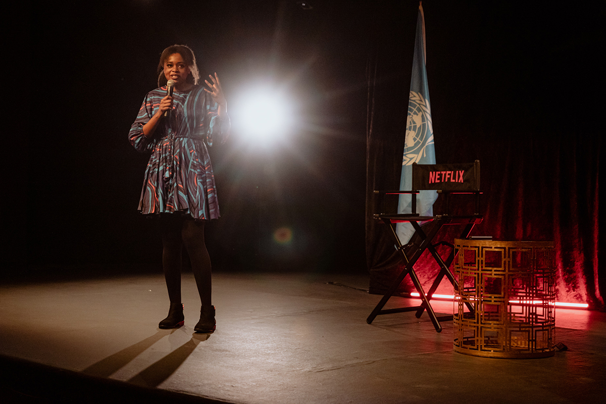 A woman speaks on a mike on stage. 