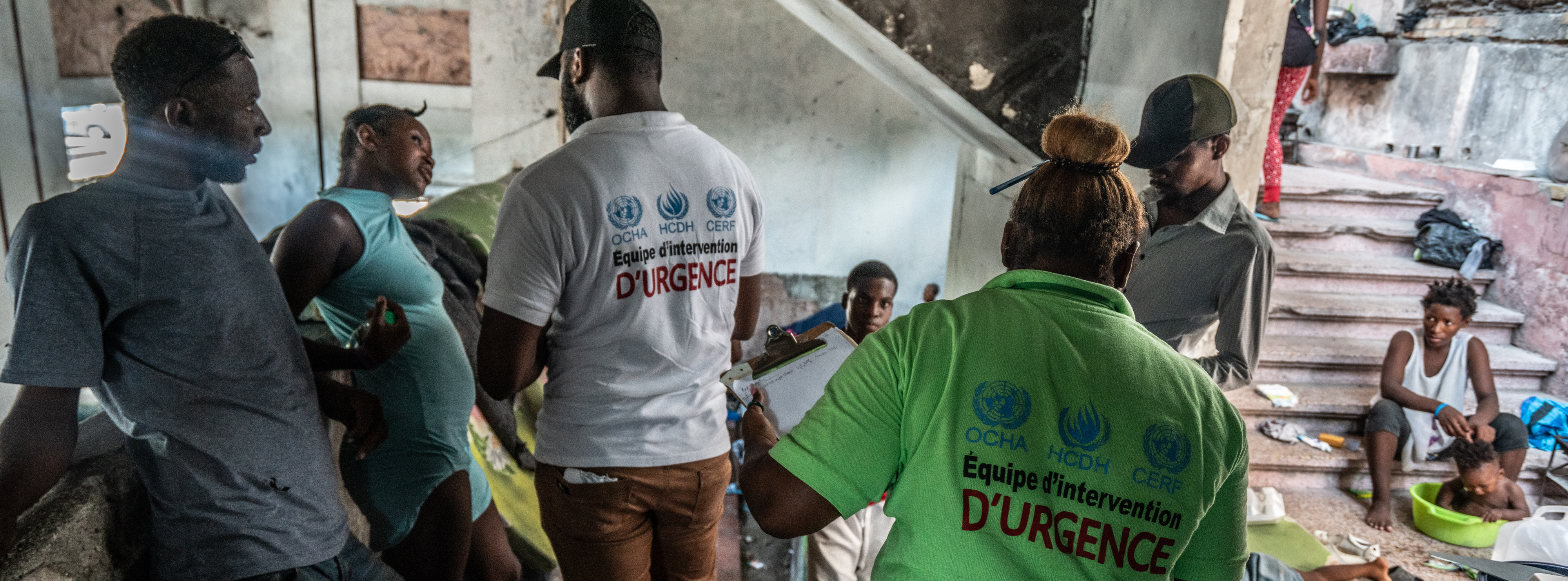 Two humanitarian workers engaged in a conversation with displaced individuals