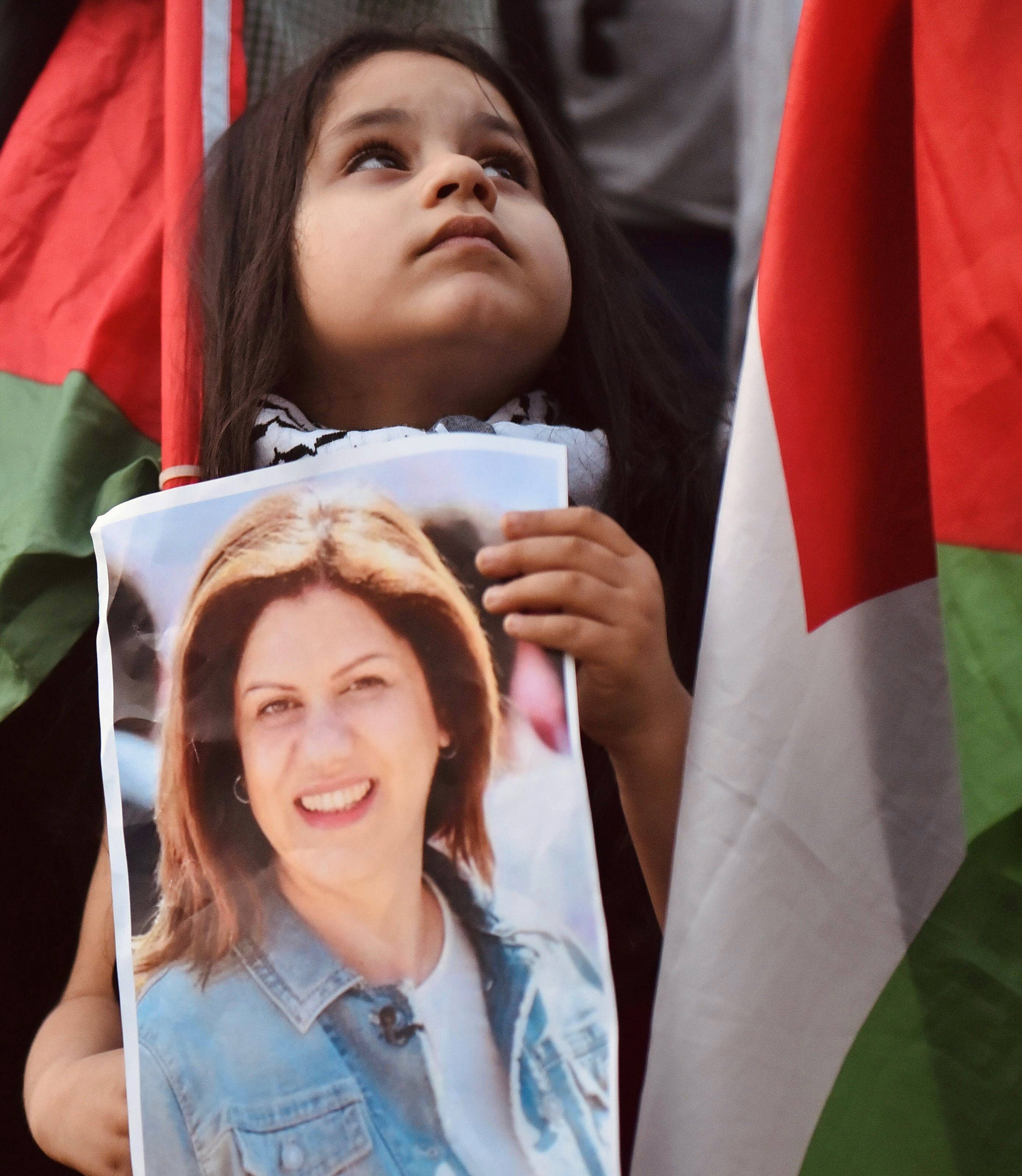 A little girl holding a portrait of Shireen Abu Akleh