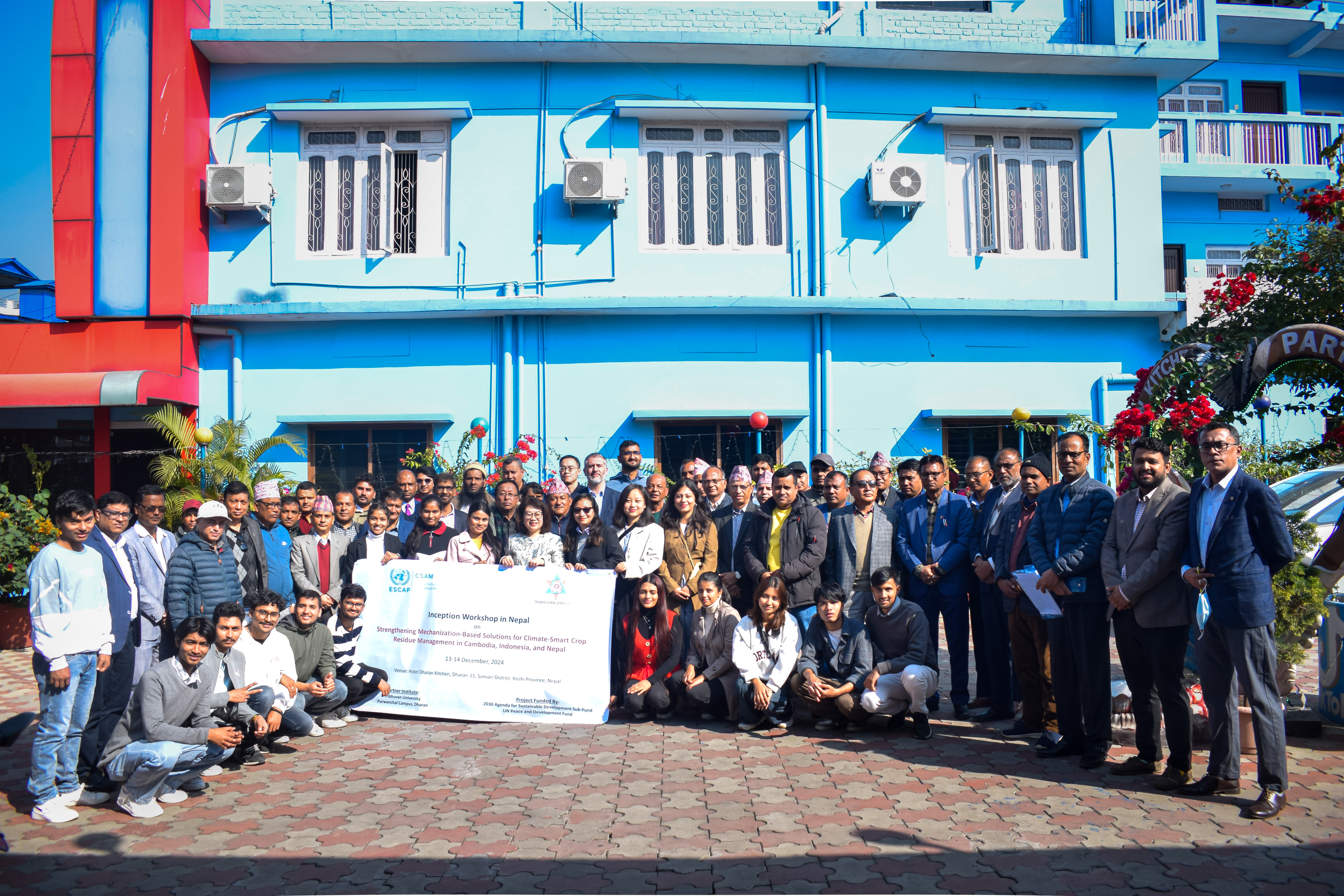 group photo outdoors with some people holding a large banner