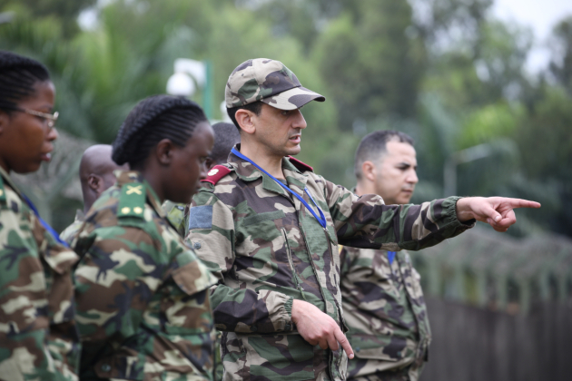 a group of men and women in uniform looking in the direction that a man is pointing towards