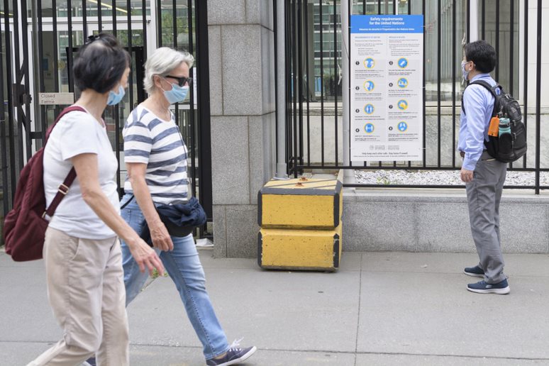 Man looks at a sign by a gated entrance.